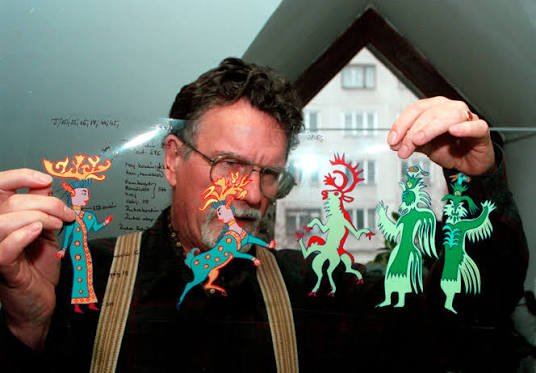 Hungarian animation director Marcell Jankovics, holding colorful paper-cut folkloric figures.